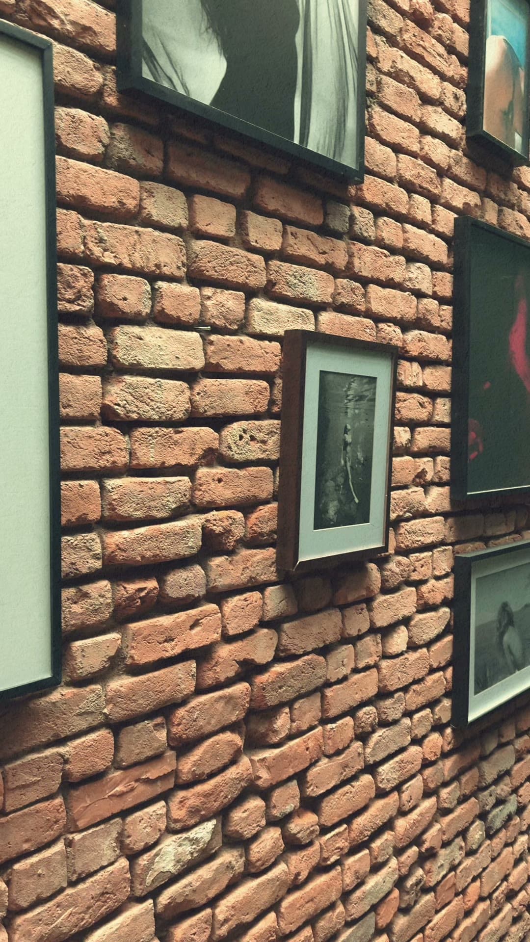 Parede de tijolos com retratos emoldurados